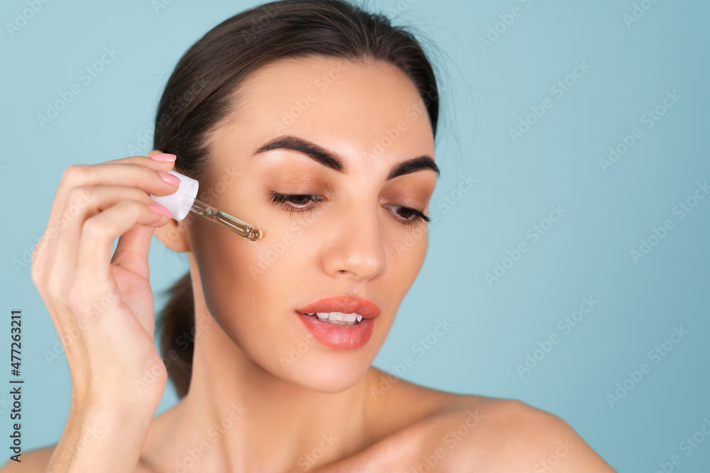 Close beauty portrait of topless woman with perfect skin and natural make-up, holds serum for youth and skin hydration, dropper with cosmetic oil