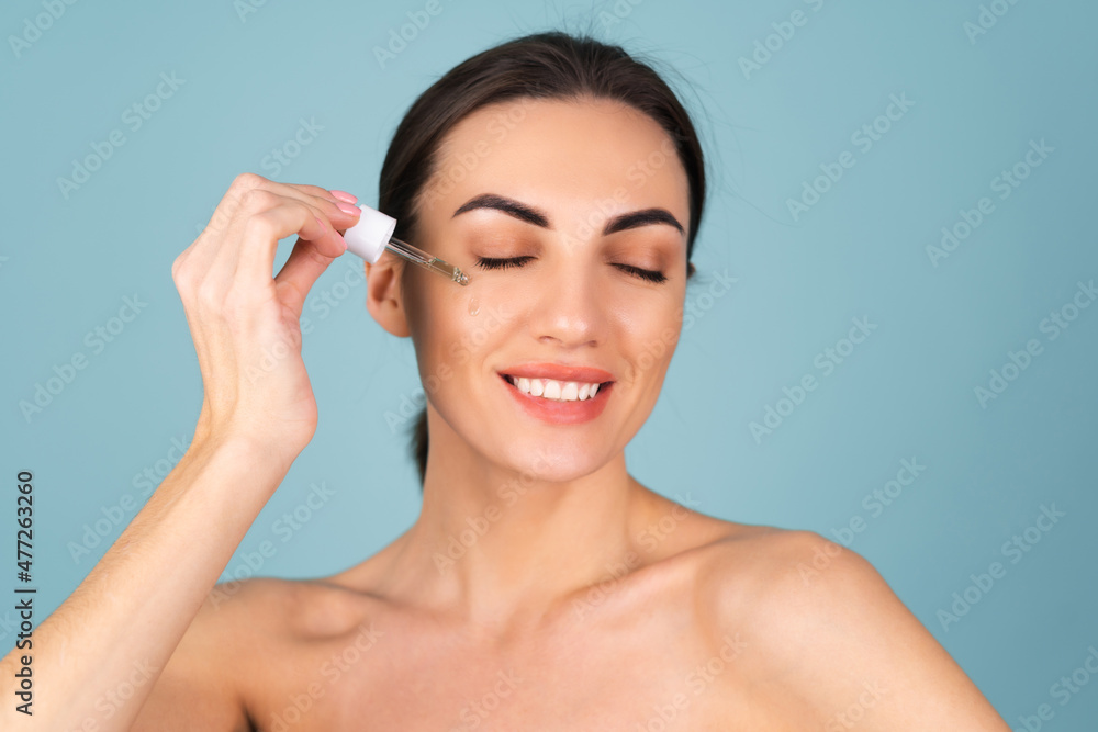 Close beauty portrait of topless woman with perfect skin and natural make-up, holds serum for youth and skin hydration, dropper with cosmetic oil Close beauty portrait of topless woman with perfect skin and natural make-up, holds serum for youth and skin hydration, dropper with cosmetic oil