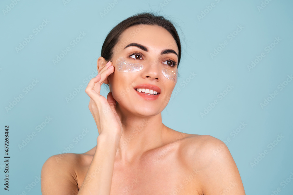 Close beauty portrait of a topless woman with perfect skin and natural make-up, shiny patches under the eyes, to moisturize the skin and relieve puffiness of the face Close beauty portrait of a topless woman with perfect skin and natural make-up, shiny patches under the eyes, to moisturize the skin and relieve puffiness of the face