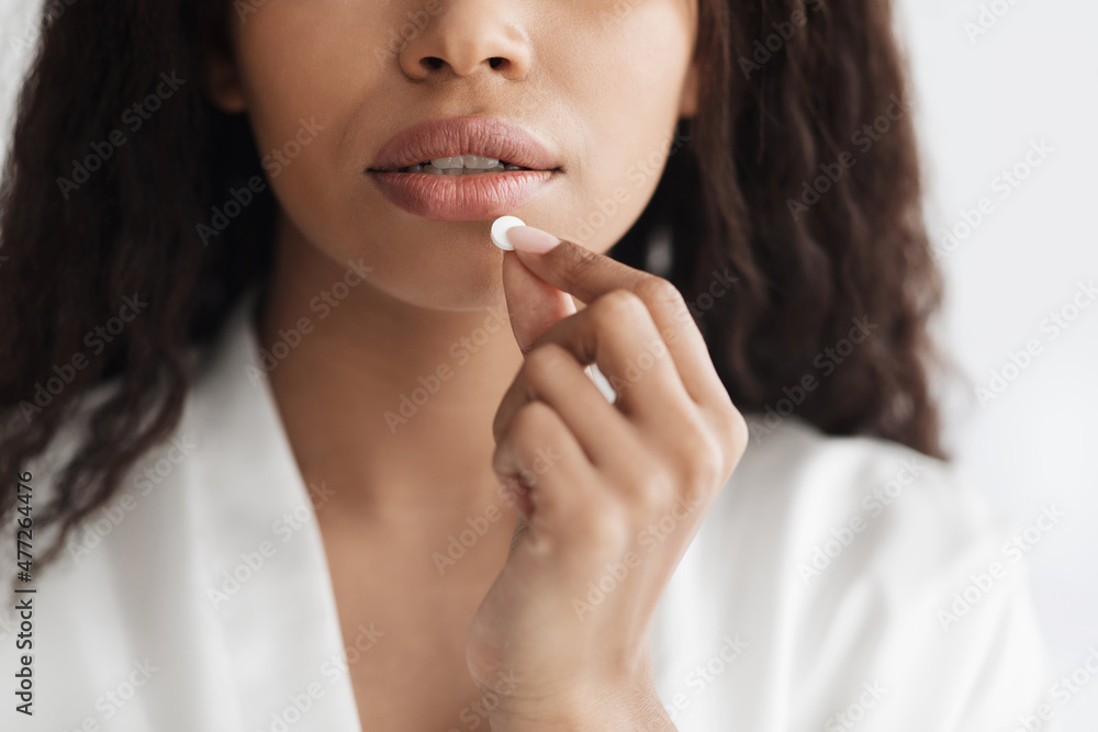 Closeup shot of african american lady taking white round pill, suffering from acute headache or migraine, crop Closeup shot of african american lady taking white round pill, suffering from acute headache or migraine, crop