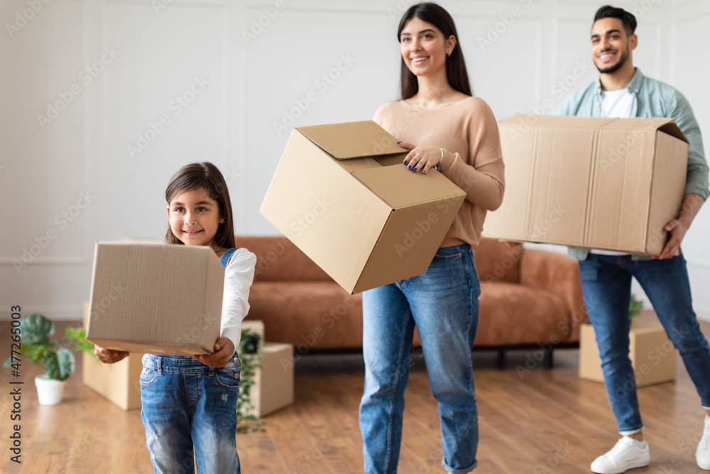 Happy young family of three carrying boxes in new flat Happy young family of three carrying boxes in new flat