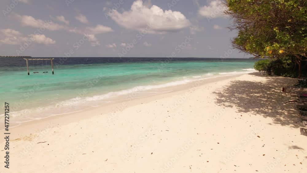 Water splashing on coastline, swing in ocean, skyline with clouds. Sandy beach and tropical forest, water splashing on Maldives island. Concept of resort and tour Water splashing on coastline, swing in ocean, skyline with clouds. Sandy beach and tropical forest, water splashing on Maldives island. Concept of resort and tour