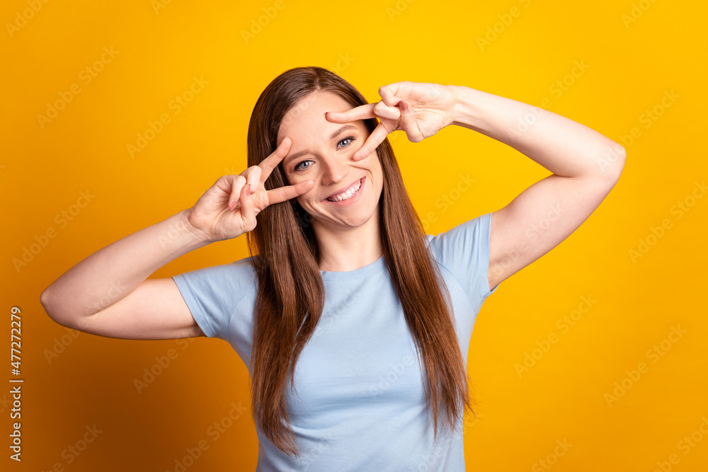 Photo of young pretty lady show fingers cool v-symbol playful glad isolated over yellow color background Photo of young pretty lady show fingers cool v-symbol playful glad isolated over yellow color background