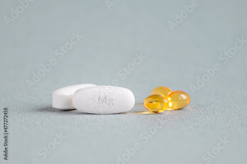 A complex of Mg ( magnesia, magnesium ) and vitamin D ( omega 3 ) capsules for treatment and human health on a light background. Copy space.
