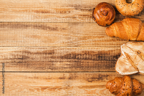 Freshly baked bread and crispy croissant for breakfast. Buns and pastries on a wooden background. Stylish banner for bakery and coffee shop with space for text