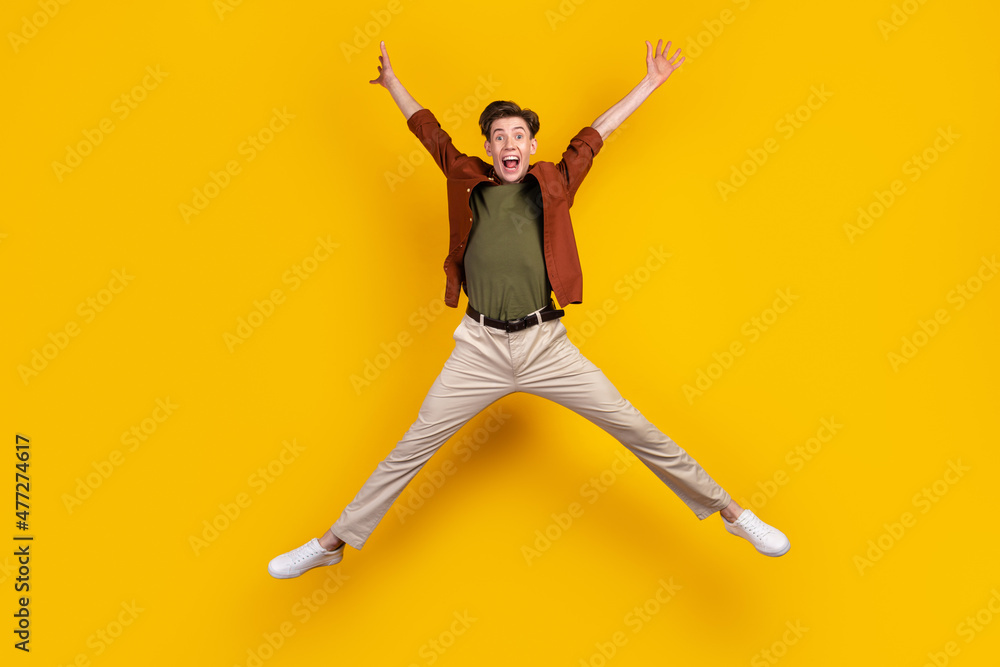 Full body photo of young excited guy have fun jump up energetic free-time isolated over yellow color background Full body photo of young excited guy have fun jump up energetic free-time isolated over yellow color background