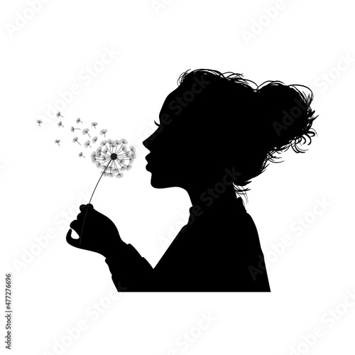 Silhouette of a young girl blowing dandelion