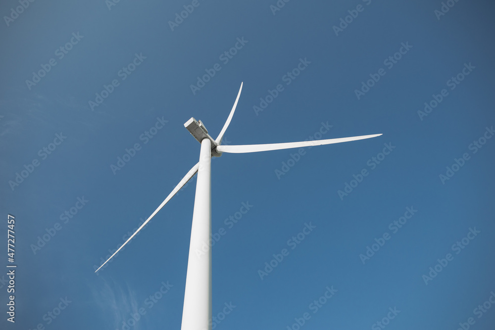 Close up of huge wind propeller working constantly on eco farm over blue sky. Concept of electric power production and clean energy. Close up of huge wind propeller working constantly on eco farm over blue sky. Concept of electric power production and clean energy.
