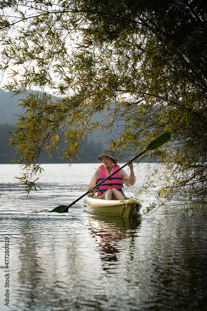 Kayaks in the lake. Tourists kayaking on mirror lake. taking photo when travel activity. woman playing in water in sunset. active woman rowing boat in lake with mountain view in evening. Kayaks in the lake. Tourists kayaking on mirror lake. taking photo when travel activity. woman playing in water in sunset. active woman rowing boat in lake with mountain view in evening.