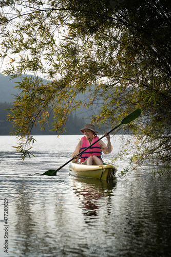 Kayaks in the lake. Tourists kayaking on mirror lake. taking photo when travel activity. woman playing in water in sunset. active woman rowing boat in lake with mountain view in evening.