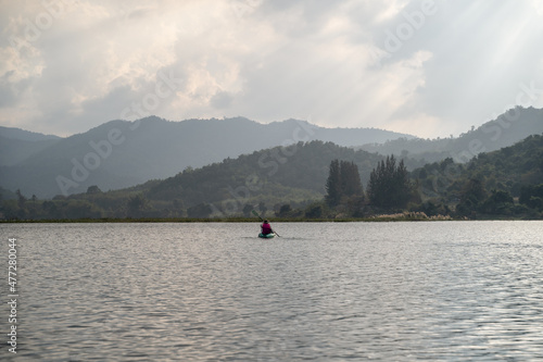 Kayaks in the lake. Tourists kayaking on mirror lake. taking photo when travel activity. woman playing in water in sunset. active woman rowing boat in lake with mountain view in evening.