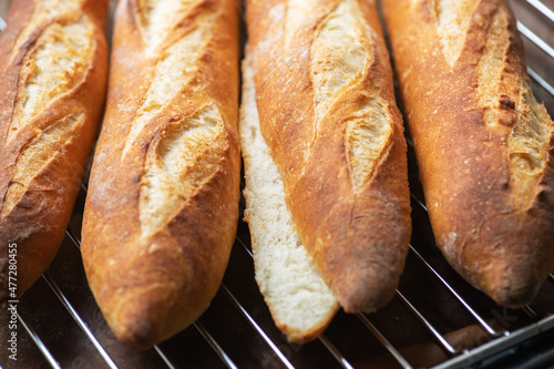 Batch of freshly baked baguettes background, whole and cutted baguettes.