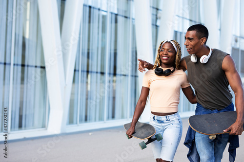 Beautiful urban couple having fun outdoors. Portrait of an excited young couple with skateboard