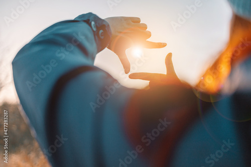 Close up of female hands making frame gesture with sunrise on an autumn meadow at sunset with sun. Business concept