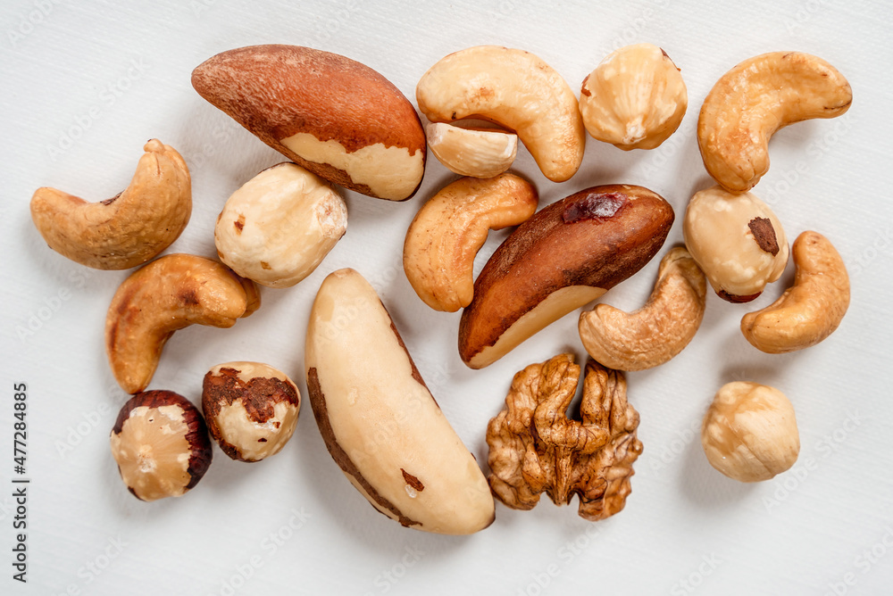 Different nuts are scattered on a white background. Walnuts, hazelnuts and Brazil nuts. The concept of healthy eating and snacking Different nuts are scattered on a white background. Walnuts, hazelnuts and Brazil nuts. The concept of healthy eating and snacking