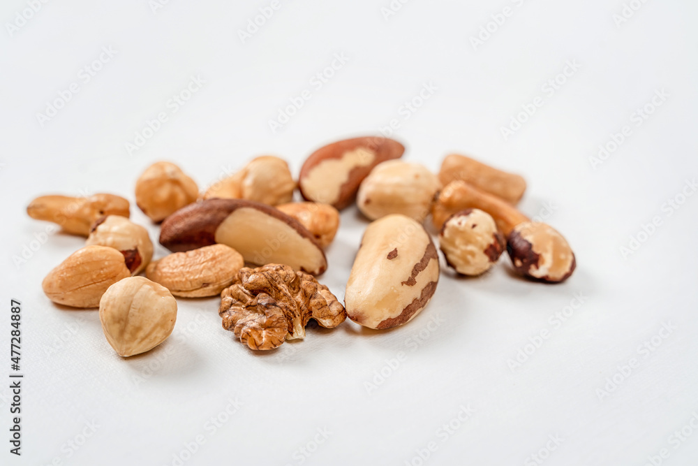 Different nuts are scattered on a white background. Walnuts, hazelnuts and Brazil nuts. The concept of healthy eating and snacking Different nuts are scattered on a white background. Walnuts, hazelnuts and Brazil nuts. The concept of healthy eating and snacking