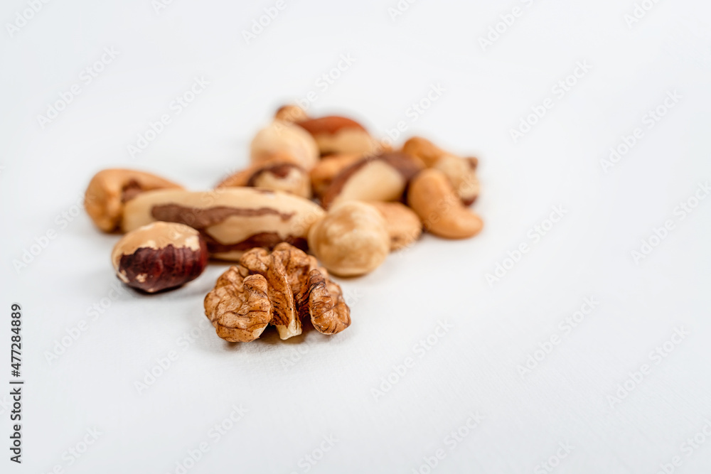 Different nuts are scattered on a white background. Walnuts, hazelnuts and Brazil nuts. The concept of healthy eating and snacking Different nuts are scattered on a white background. Walnuts, hazelnuts and Brazil nuts. The concept of healthy eating and snacking