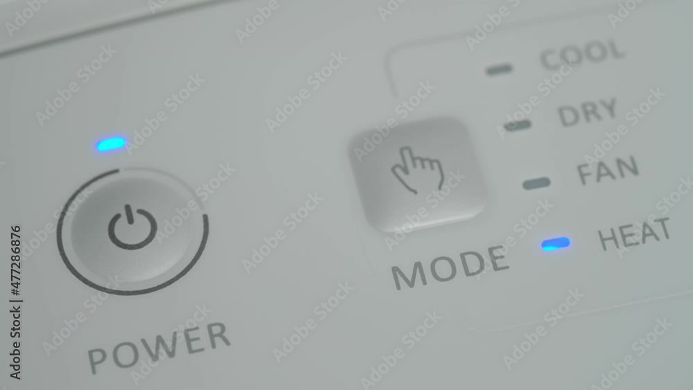 The person presses the start button with his finger on a mobile air conditioner to warm up the room in winter. Close-up. The person presses the start button with his finger on a mobile air conditioner to warm up the room in winter. Close-up.