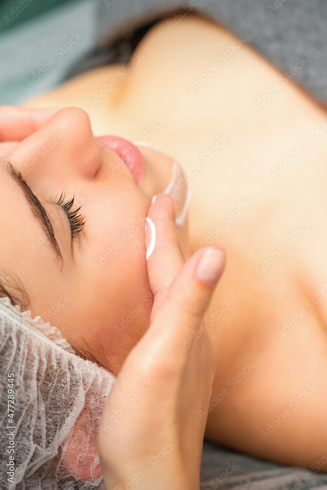 Spa facial skincare. Close-up of a young caucasian woman getting spa moisturizing face massage treatment at beauty spa salon