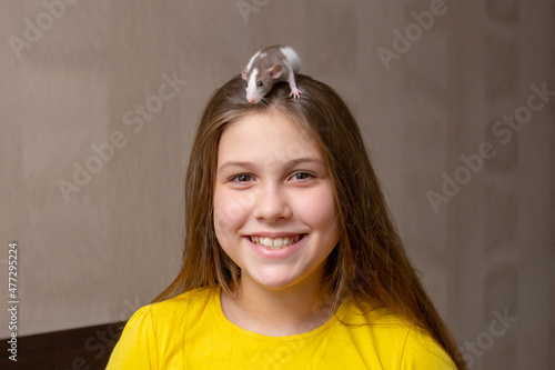 a small pet rat of white-gray color on the head of a smiling girl