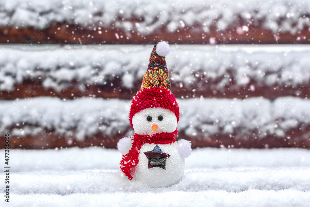 Fototapeta premium Merry christmas and happy new year greeting card with copy space Happy little snowman in red cap and scarf standing in winter snow background Xmas fairytale Hello January, February concept