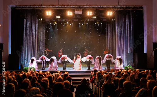 A collective of musicians, singers and dancers in gypsy costumes perform on stage. photo