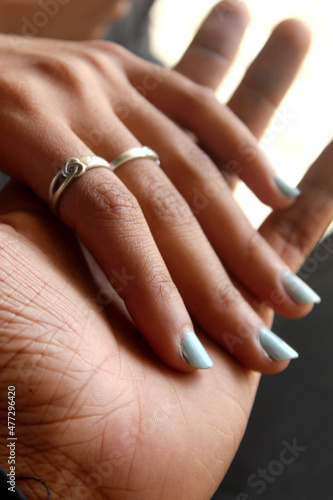 Closeup of loving couple holding hands with ring. Hands held together  selective focus with blur background 