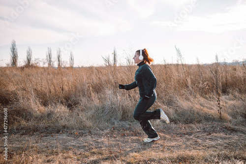 Sportive young woman runs in the park and listens to music. Sports lifestyle. © Shi 