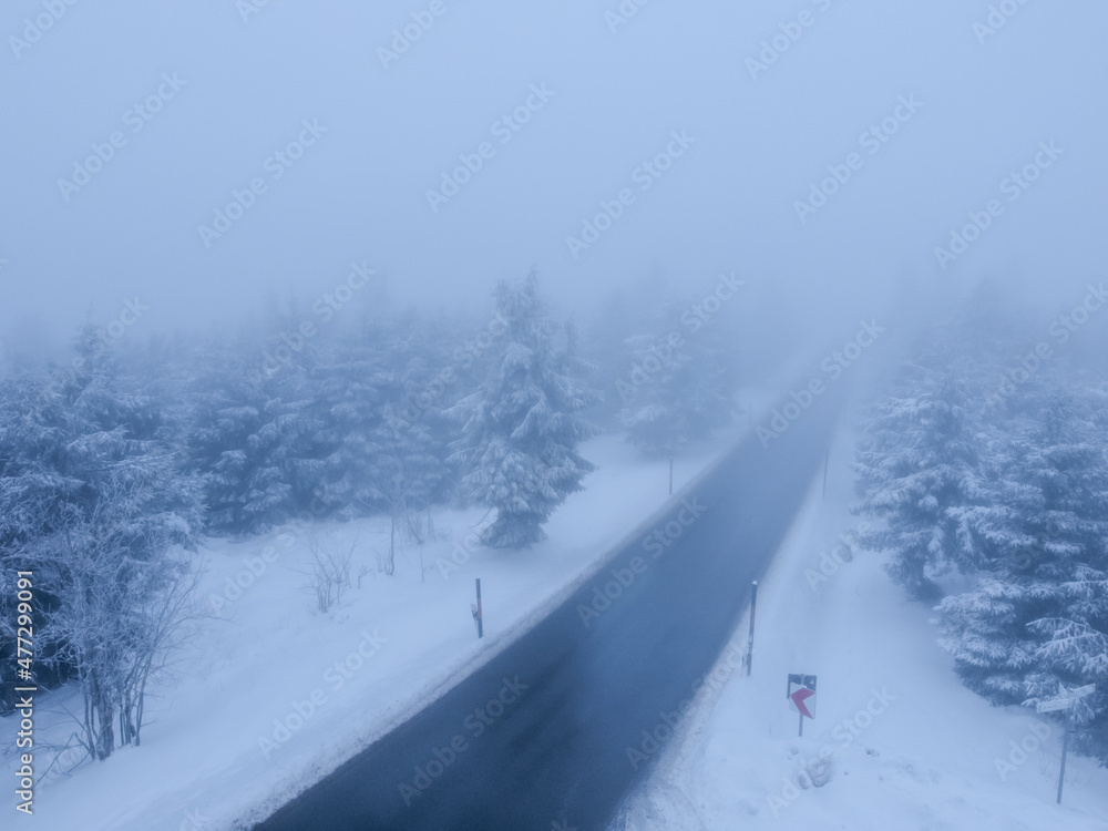 Fototapeta premium Road in the fog in a wintry landscape from above