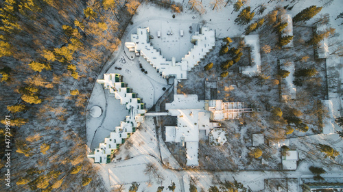 Aerial view of the postmodern sanatorium building surrounded by forest. Winter sunny day