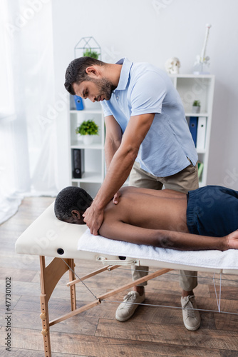 rehabilitologist doing massage to mature african american patient