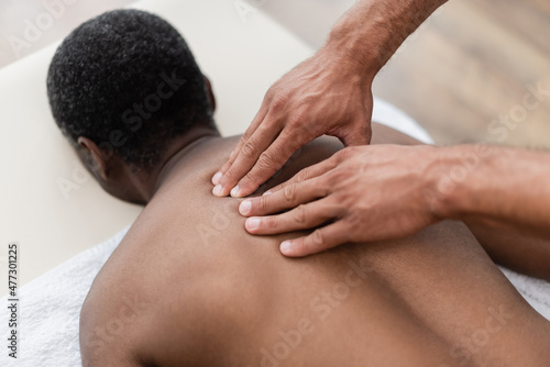 african american man getting back massage during treatment in rehab center