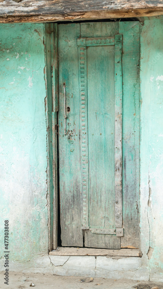 old and weathered or worn green wooden door of village house.