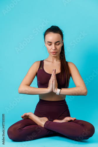 beautiful sportive brunette woman is engaged in yoga, sits in the lotus position on a blue background. isolated