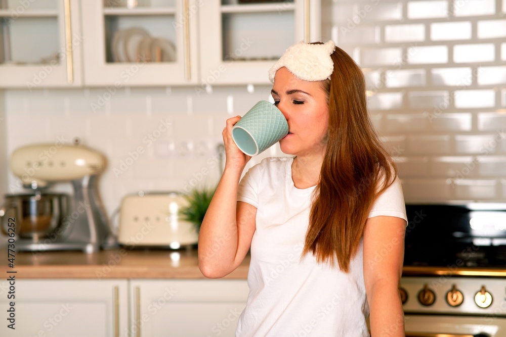Contented, sweet woman drinking coffee in her kitchen at home. Cute female holding a mug. good morning Contented, sweet woman drinking coffee in her kitchen at home. Cute female holding a mug. good morning