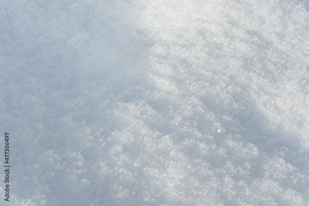 Sun shines on ground covered with snow forming small hills - closeup macro detail