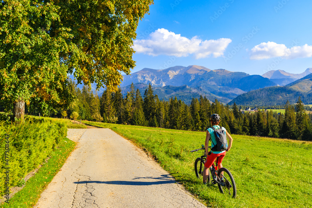 Obraz premium Young woman on bike looking at beautiful panorama of Tatra Mountains, Poland