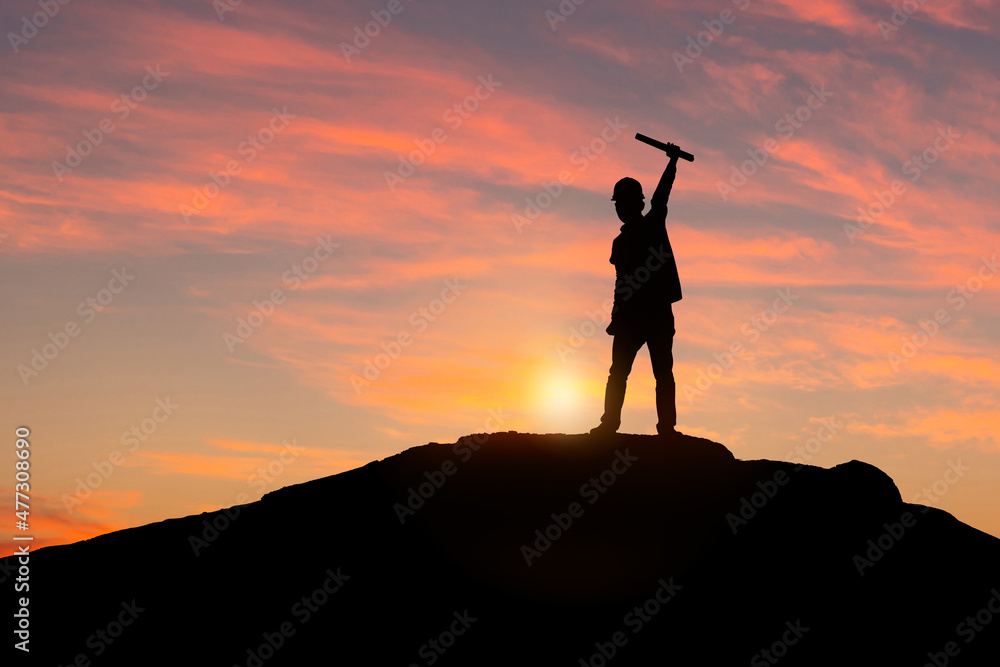 Silhouette of Engineer man standing celebration success enjoying on a mountain top tropical sunset, Happiness and active life concepts