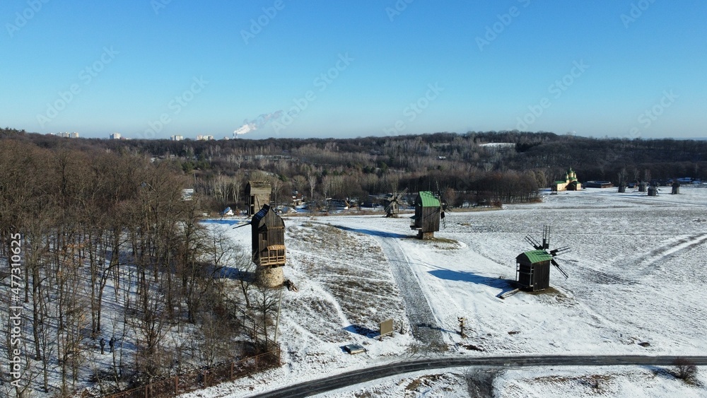 Old abandoned windmills in a snowy field.  Pyrohiv museum Kyiv, Ukraine