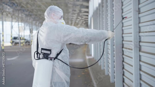 Wallpaper Mural Worker wearing protective suit disinfection gear disinfect surface public place parking. Side view of disinfector safety overall and respiratory mask Covid pandemic Medium shoot Torontodigital.ca