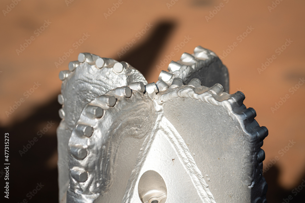 A polycrystalline carbide drill bit, using for drill a subsurface rock structure in oil drilling operation. Oil industrial heavy equipment object photo. Close-up and selective focus. - obrazy, fototapety, plakaty 