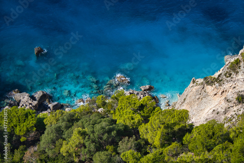 sunny clear blue sea with green trees at cliff 