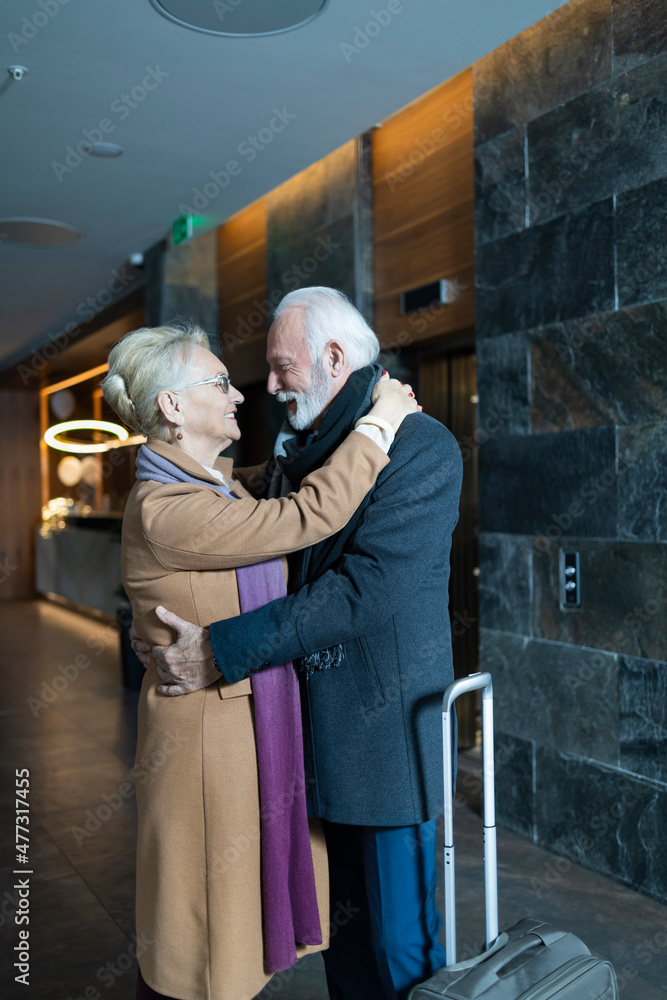 Elderly wife and husband hugging in a hotel