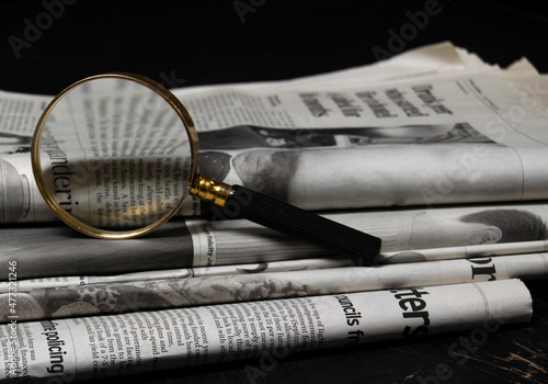 Magnifying glass and newspapers. Concept for fact check, detective search