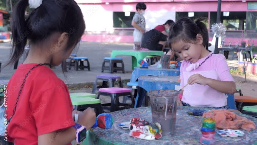 Slow motion scene of 5-year-old Asian girl sits and paints plaster cartoon characters. Slow motion scene of 5-year-old Asian girl sits and paints plaster cartoon characters.