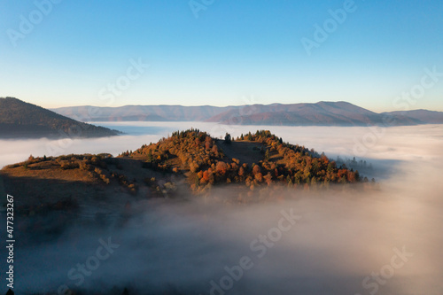 Thick layer of fog covering rainbow mountains with colorful trees