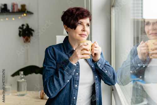 Woman with beverage looking out window