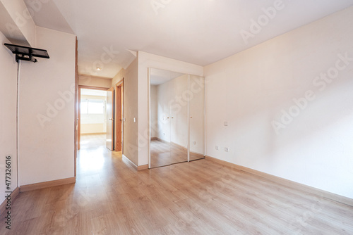 Bedroom with built-in wardrobe and mirrored doors with light wooden floor