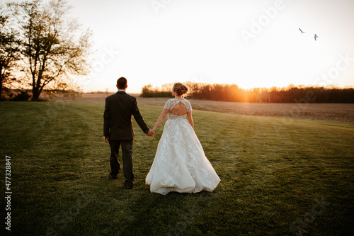 Foto Bride and Groom hold hands at sunset