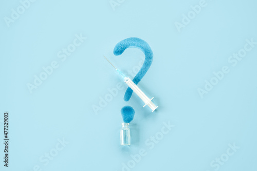 Covid 19 vaccine side effects. Vaccine Storage and Handling. Spilled medicine vial bottle, question mark and syringe on blue background © irissca